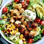 Santa Fe Salad with grilled chicken, avocado, black beans, corn, tomatoes, romaine, and creamy dressing in a large bowl.