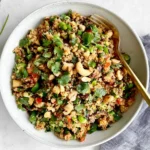 Vegan Thai Quinoa Salad with edamame, fresh cilantro, green onions, red peppers, and crunchy nuts in a flavorful dressing.