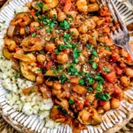Italian Stewed Zucchini and Chickpeas with tomatoes, tender zucchini, fresh parsley, herbs, and fluffy rice on a rustic plate.