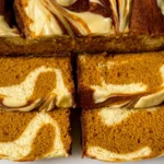 Pumpkin Cheesecake Bread sliced to reveal a moist spiced pumpkin crumb with rich, creamy cheesecake swirls.