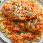 Slow Cooker Creamy Tomato Basil Chicken Breast served over fettuccine pasta with creamy tomato sauce and fresh basil