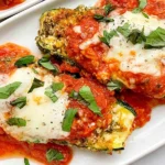 Three Cheese Zucchini Parmesan with crispy breaded zucchini, marinara sauce, melted cheese, and fresh basil on a white platter.