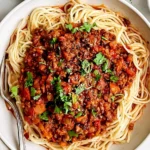 Vegan Lentil Bolognese with spaghetti, rich tomato lentil sauce, vegetables, and fresh chopped herbs