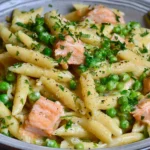 Salmon and Pea Pasta with Lemon featuring flaky salmon pieces, creamy penne pasta, vibrant green peas, and fresh parsley in a rich lemon crème fraîche sauce.