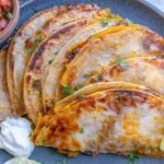 Pumpkin and Black Bean Tacos with melted cheese, cilantro, pico de gallo, sour cream, and a fresh lime wedge.